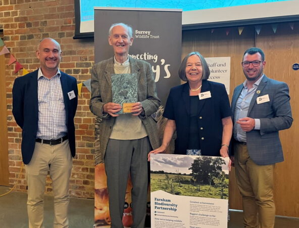 Four people smiling. One is holding a display panel.