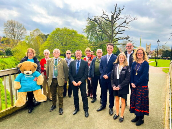 Group of people standing on a bridge with trees in background.