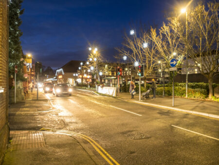 Trees decorated with snowflake Christmas lights next to a road