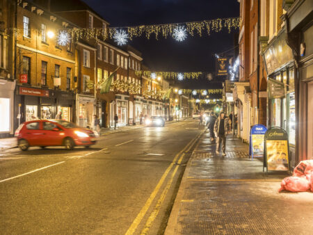 A town centre, row of Georgian buildings with a road running through it and Christmas lights