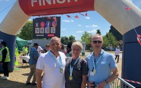 Three people standing under an inflatable 'finish' line wearing medals.
