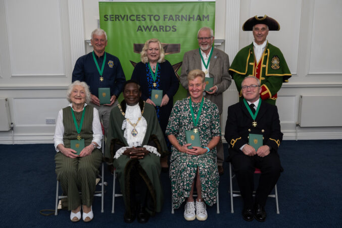 Seven people sitting alongside the Mayor and Town Crier.