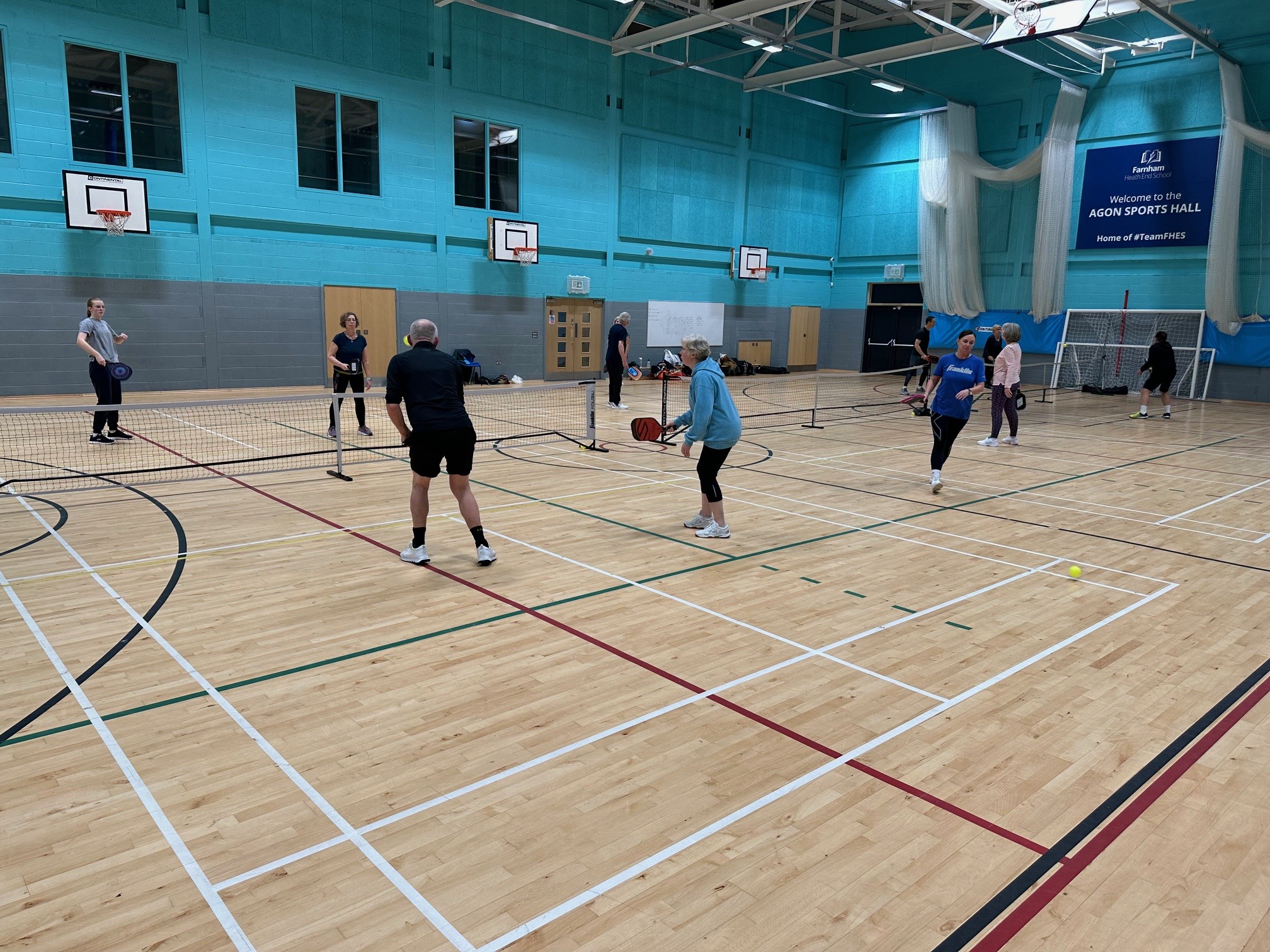 People in a sports hall playing pickleball