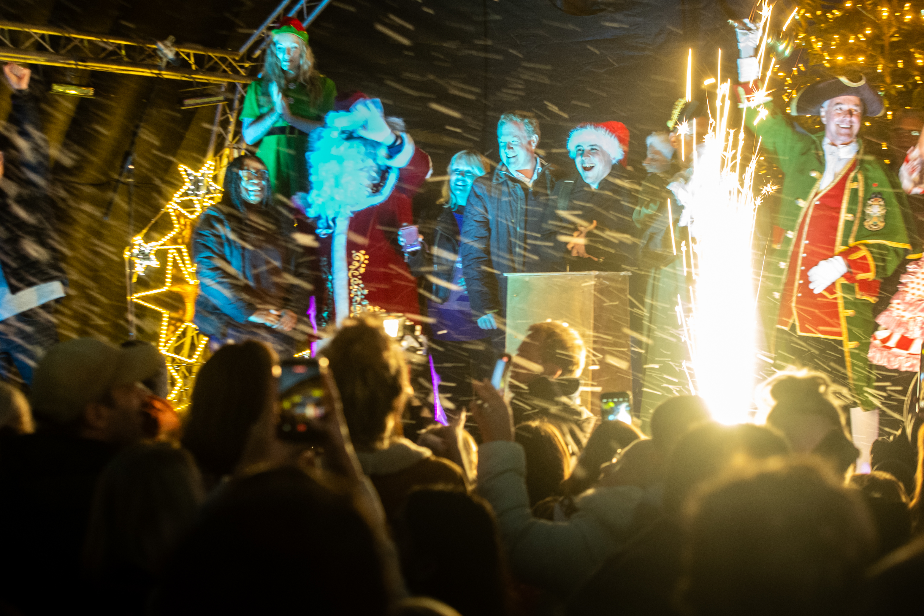 Crowd watching a group of people on stage as they switch on the Christmas lights.