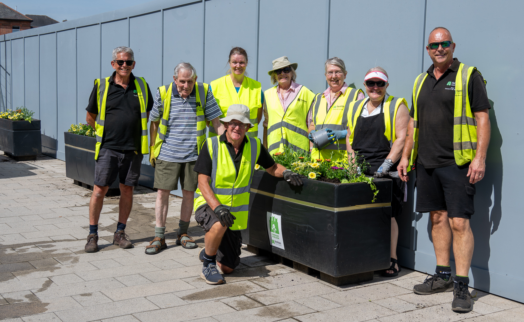 Group of people standing around a large planter.