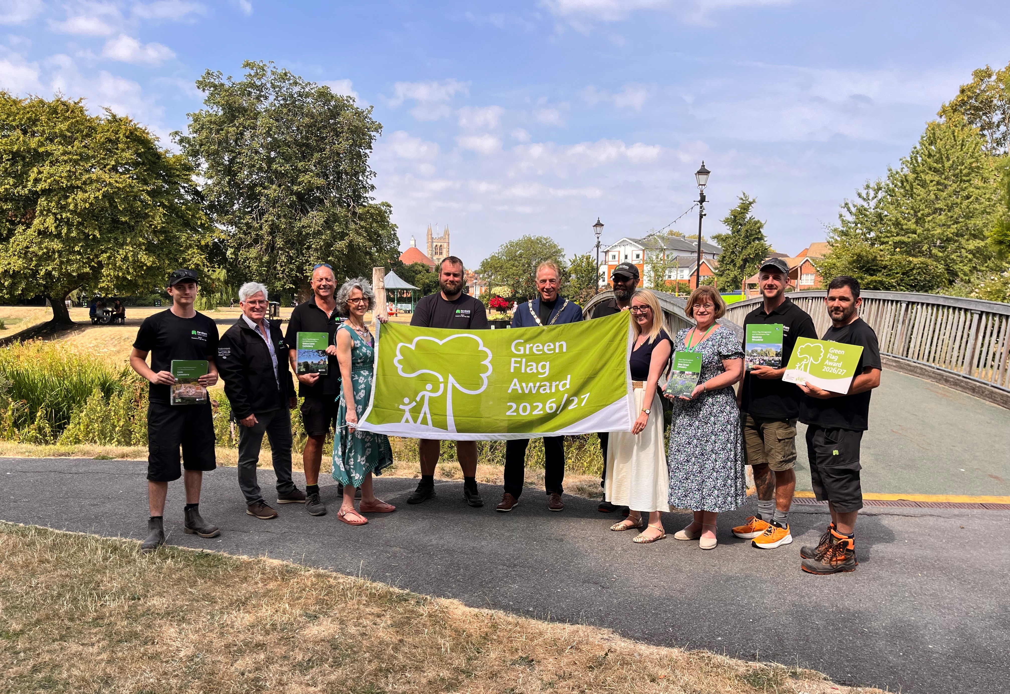 Group of people in a park holding a flag that says Green Flag Award 2026/27.
