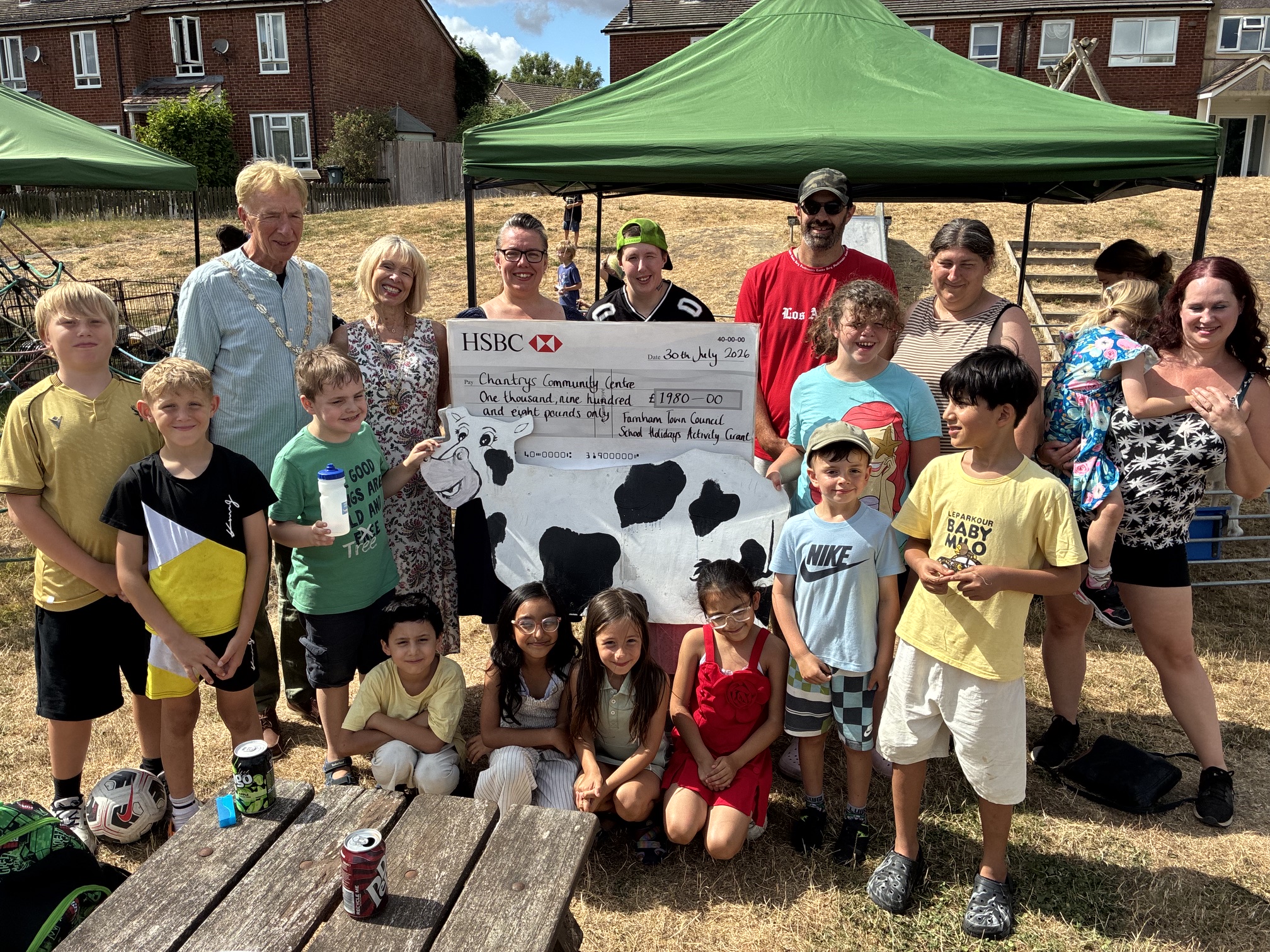 Group of children and adults surrounding a large cheque.